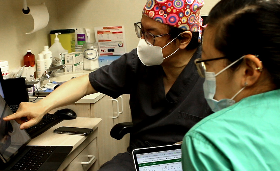 Doctor Hong and Doctor Chan reviewing patient photos of skin cancer. 